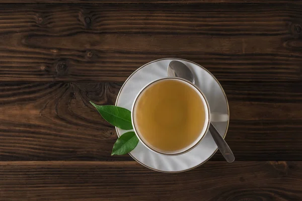 Té casero fresco en un vaso blanco y platillo sobre una mesa de madera. La vista desde arriba . —  Fotos de Stock