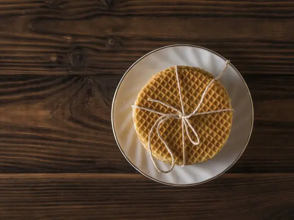 Tahta bir masada beyaz bir tabakta karamel kremalı waffle. Düz yatıyordu. — Stok fotoğraf