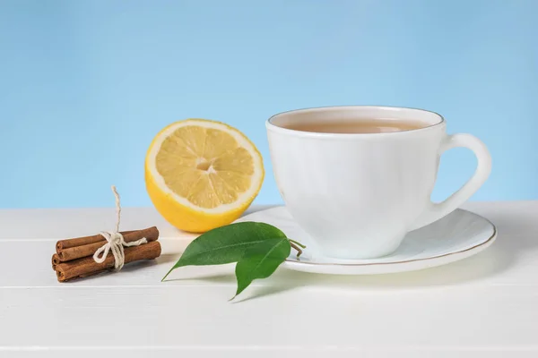 Té con limón y canela en un tazón blanco sobre una mesa blanca . — Foto de Stock