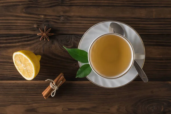 Vista superior de una taza de té con limón y canela sobre una mesa de madera. Puesta plana . — Foto de Stock