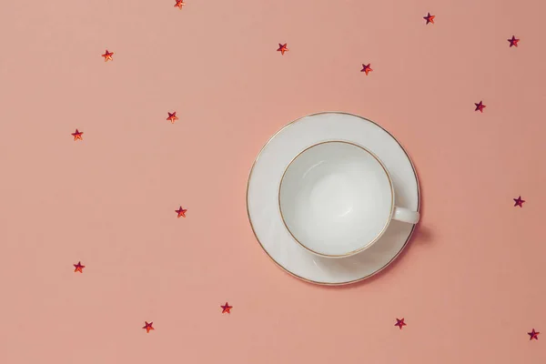 Taza de café blanco con platillo sobre fondo rosa con estrellas . — Foto de Stock