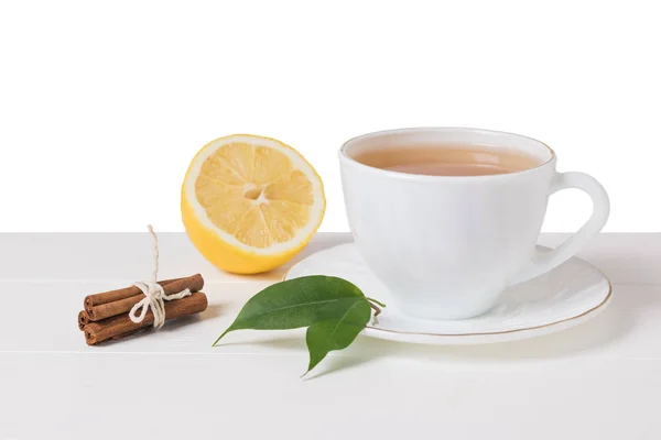 Té, canela y limón sobre una mesa de madera blanca aislada sobre un fondo blanco . —  Fotos de Stock