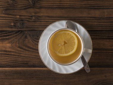 Gövde üzerinde metal bir kaşık ve ahşap bir masada limonlu bir fincan çay. Düz yatıyordu.