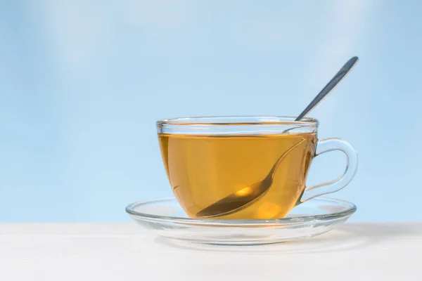 A metal spoon in a glass Cup of tea on a white table. — 图库照片