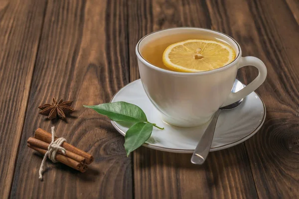 Una taza de té fresco con limón y canela en una mesa de madera al sol . — Foto de Stock