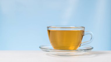 Bardakta çay ve mavi arka planda beyaz bir masada çay..