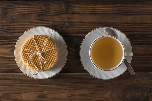 Hausgemachte Waffeln und Tee mit Zimt und Zitrone auf einem Holztisch. flache Lage. — Stockfoto