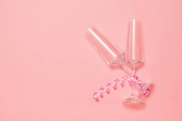 Dos copas de champán con una cinta rosa sobre un fondo rosa . — Foto de Stock