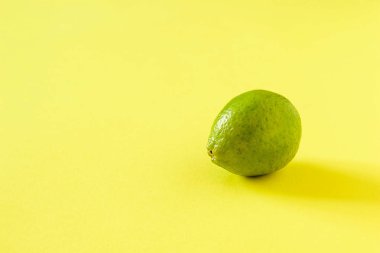 Ripe green lime on a yellow background.