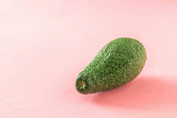 Большой спелый красивый зеленый авокадо на розовом фоне . — стоковое фото