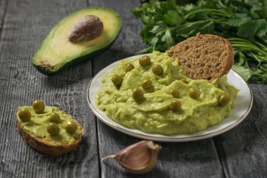 Tahta bir masada guacamole ve yeşil bezelye ile ekmek. Diyet vejetaryen Meksika yemeği avokadosu..