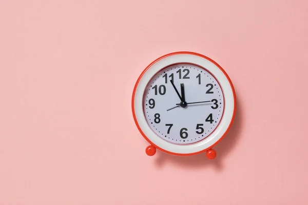นาฬิกาปลุกสีแดงที่มีหน้าปัดสีขาวบนพื้นหลังสีชมพู . — ภาพถ่ายสต็อก