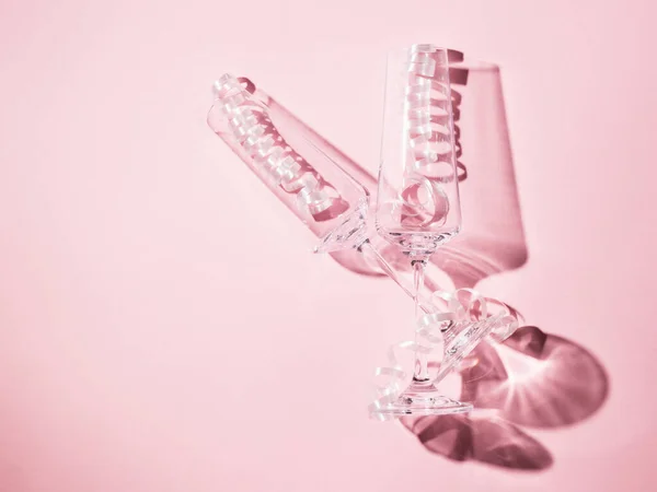 Dos copas de champán llenas de serpentina sobre un fondo rosa . — Foto de Stock