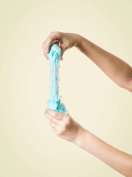 Stretched turquoise slime in hands on a yellow background. — 스톡 사진