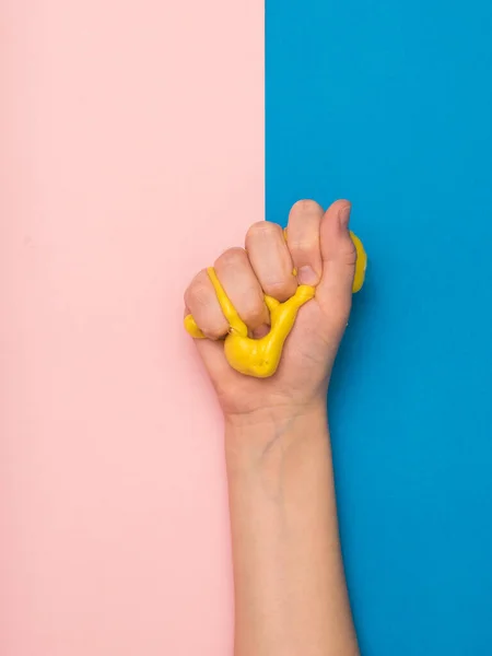 A yellow slime clenched in his fist against a pink and blue background.