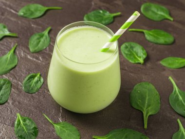 Smoothie 'li bir bardak ve ıspanak yapraklarını taştan bir arka plana serpin. Fitness ürünü.