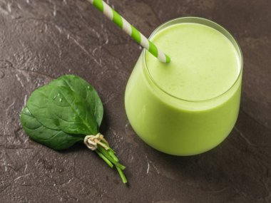 Bir sürü ıspanak yaprağı ve arka planda buzlu içecek olan bir cam bardak. Fitness ürünü.