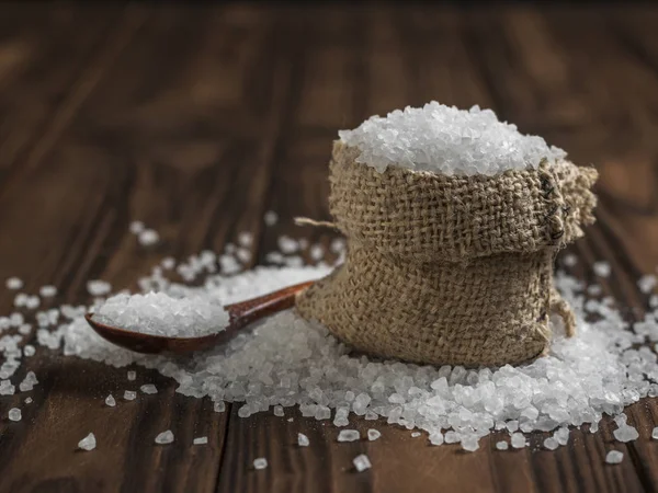 Una bolsa de sal gruesa y una cuchara de madera sobre una mesa rústica . —  Fotos de Stock