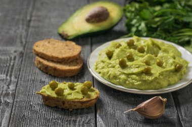 Guacamole with green peas and bread on a rustic table. Diet vegetarian Mexican food avocado.