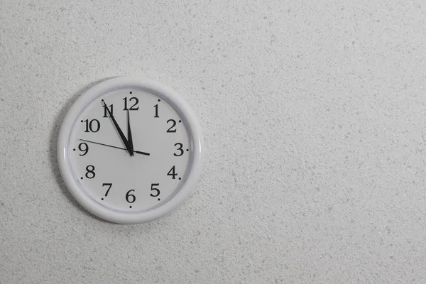 Całodobowo biały zegar z rękami na lekkiej teksturowanej ścianie. — Zdjęcie stockowe