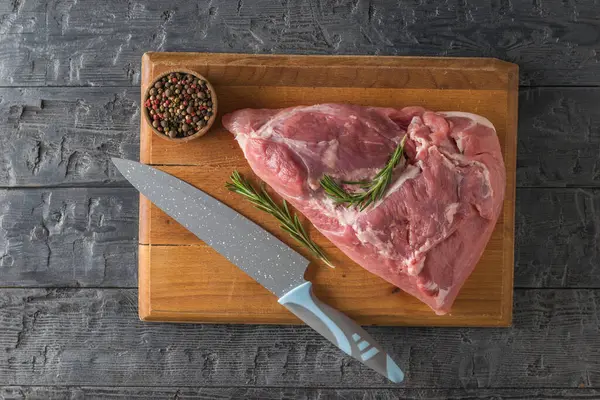 A piece of pork meat on a cutting Board with a knife and seasonings. The view from the top. — Stock Fotó