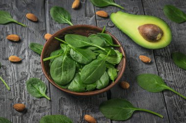 Avocado, spinach leaves and almonds on a wooden table.