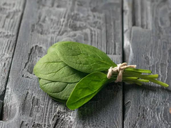 Freshly picked spinach leaves tied with a rope on a wooden table. Food for fitness. — Stockfoto