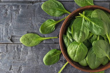 Taze ıspanak yaprakları masaya ve kilden bir kaseye saçılmıştır. Fitness için yemek. Yukarıdan görünüşü.