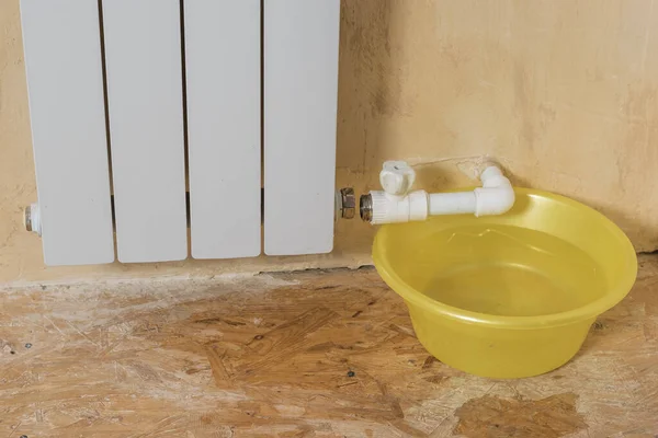在漏水的散热器下面的一个大的黄色碗.私人住宅供热系统的事故. — 图库照片