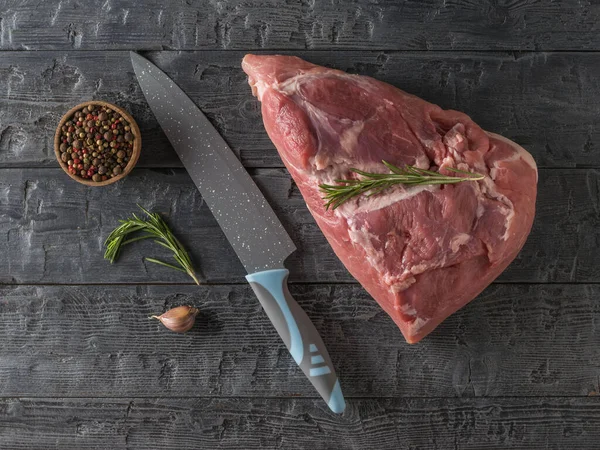 Egy nagy húsvágó kés és egy nagy darab sertéshús egy fából készült asztalon. A kilátás felülről. — Stock Fotó