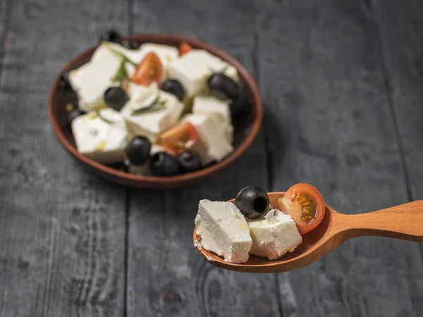 Spoon with feta cheese salad with tomatoes and olives.