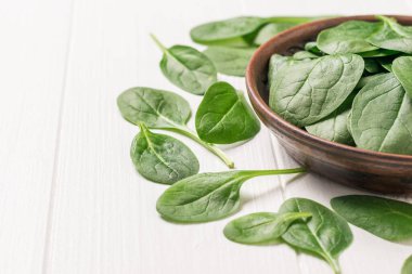 Beyaz ahşap bir masada ıspanak yapraklı eski bir kase. Fitness için yemek. Yukarıdan görünüşü.