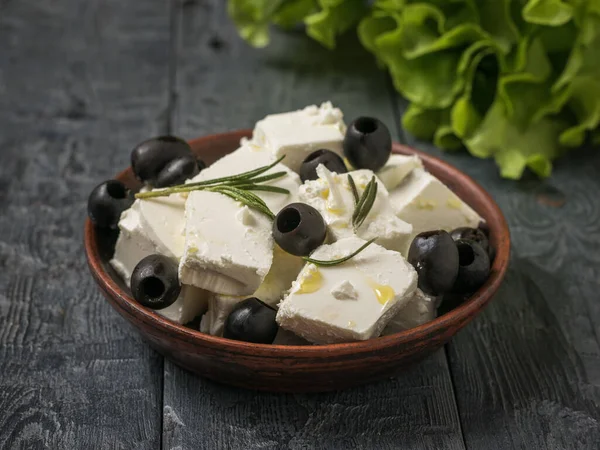 Feuilles de laitue et un bol de fromage feta et d'olives sur une table en bois . — Photo