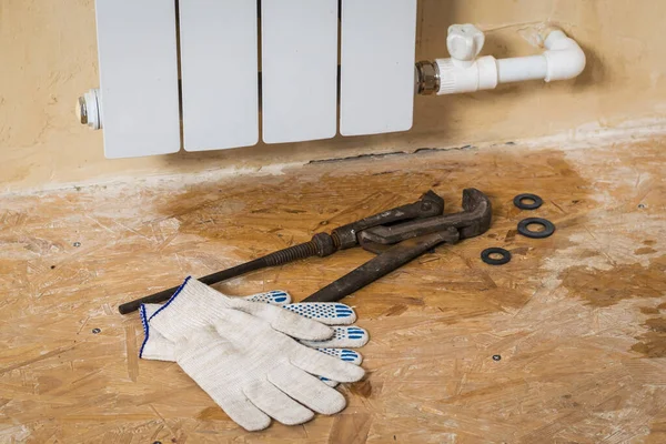Gloves and tools for repairing a leaking radiator. Accident of the heating system of a private house. — 图库照片