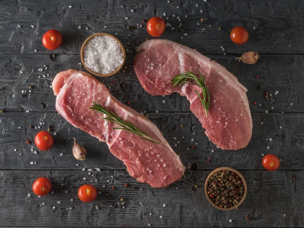 Dos filetes de cerdo con tomates cherry en una mesa de madera. La vista desde arriba . —  Fotos de Stock