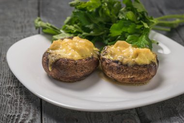 Maydanoz yapraklı beyaz tabakta peynirli fırında mantar..