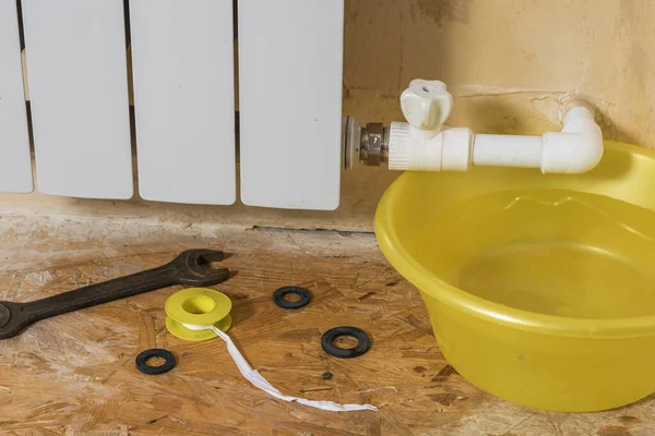A yellow water basin and a set of tools near a leaking radiator. Accident of the heating system of a private house. — Stok fotoğraf