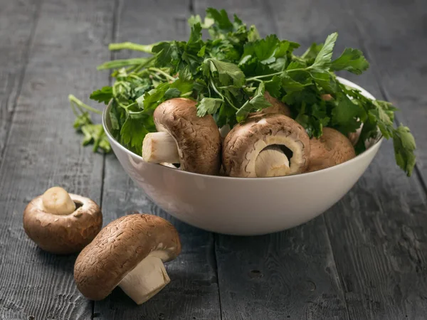 Parsley leaves in a white bowl with Royal mushrooms on a wooden table. Vegetarian food. — Stockfoto