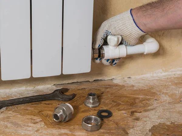 A man turns off a leaking radiator in a private home. Accident of the heating system of a private house. — 图库照片