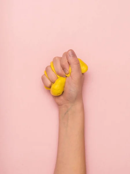 Детский кулак сжимает желтую слизь на розовом фоне . — стоковое фото