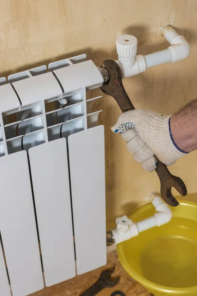 Un homme répare une fuite de radiateur dans une maison privée. Accident du système de chauffage d'une maison privée . — Photo