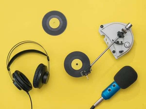 Винтажный плеер, играющий желтый виниловый диск, наушники и микрофон на желтом фоне . — стоковое фото