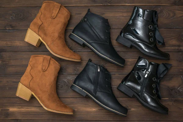 Um conjunto de três pares de sapatos de couro feminino em um fundo de madeira . — Fotografia de Stock