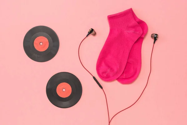 Meias vermelhas, fones de ouvido vermelhos e dois discos de vinil vermelho em um fundo rosa. Depósito plano . — Fotografia de Stock