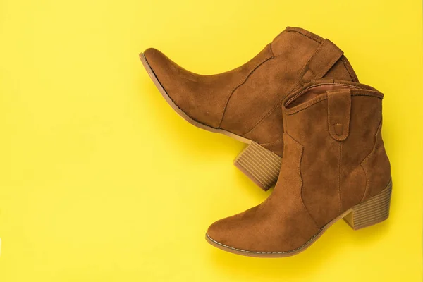 Sarı arka planda topuklu iki süet bot..