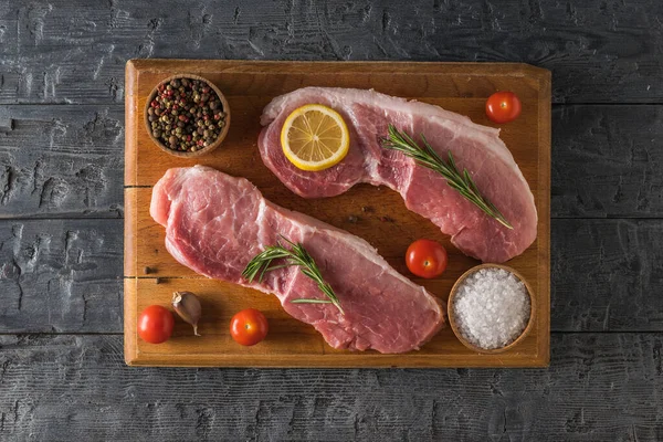 Dos filetes de cerdo en una tabla de cortar con pimienta y especias. La vista desde arriba . —  Fotos de Stock
