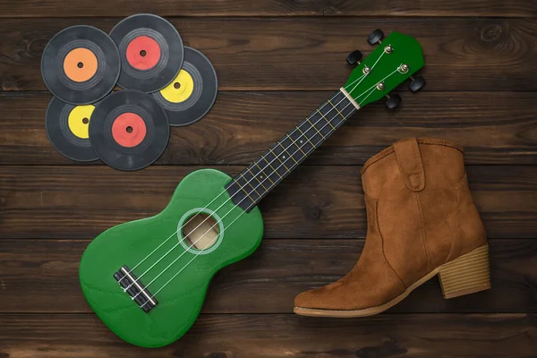 Замшевый ботинок, виниловые диски и гитара на деревянном фоне . — стоковое фото