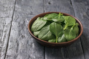 Ahşap bir masada ıspanak yapraklı sığ bir kil tabağı. Zindelik için yemek.