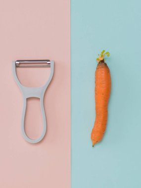 Pembe ve mavi arka planda soyucu ve havuç. Düz yatıyordu.