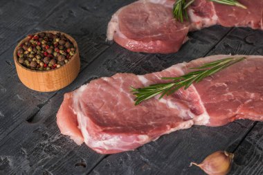 Biberli ahşap bir fincan ve ahşap bir masada iki domuz bifteği..